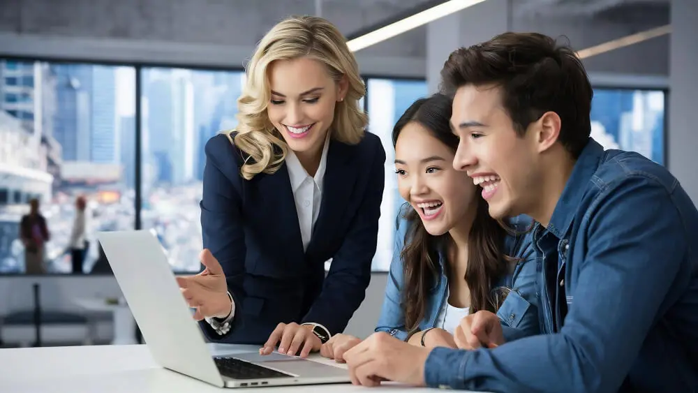 Three individuals engaged in discussion while viewing a laptop screen together.